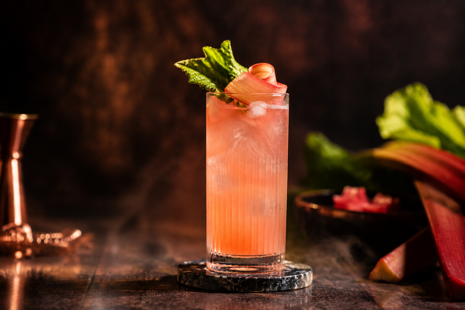 Cocktail Gin Rhubarbe HEPP servi dans un verre long drink avec coulis de rhubarbe maison, glace, feuille fraîche et ruban de rhubarbe dans une ambiance de mixologie haut de gamme.